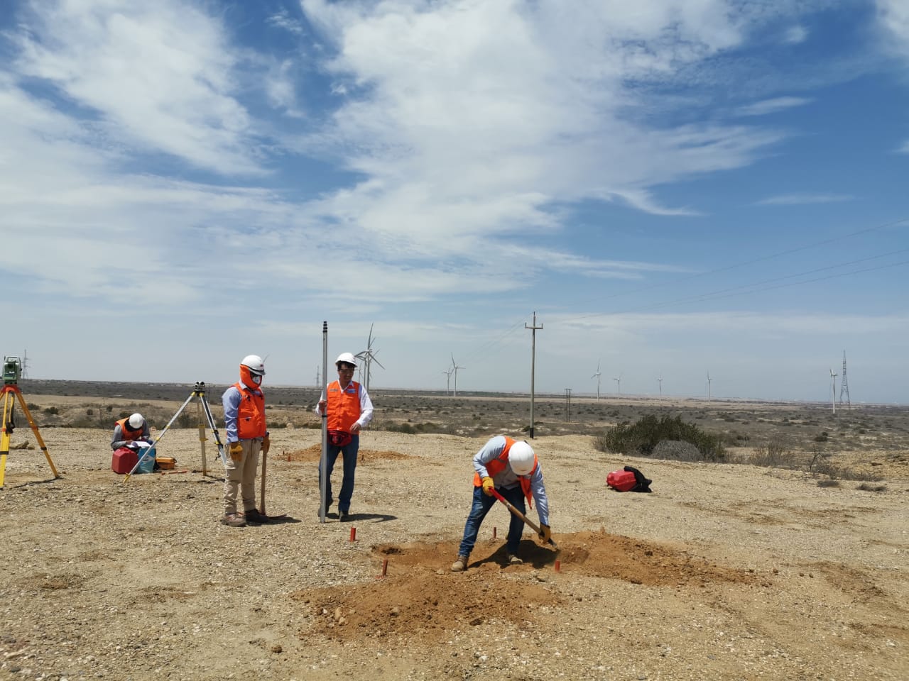 Civil construction crew surveying helical pile locations at a powerline site