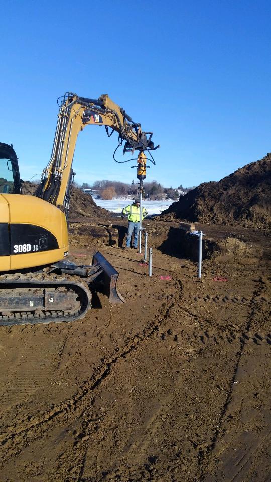 Helical foundation pile installation on a winter construction site